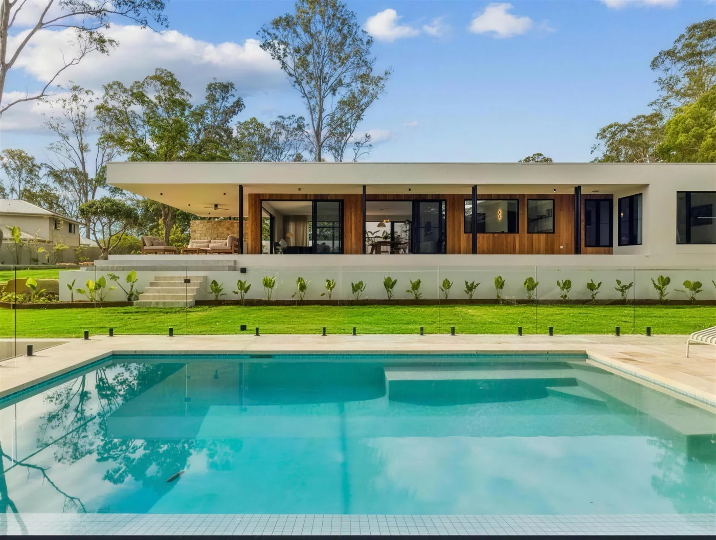 Smooth white rendered home beside a pool on an acreage block