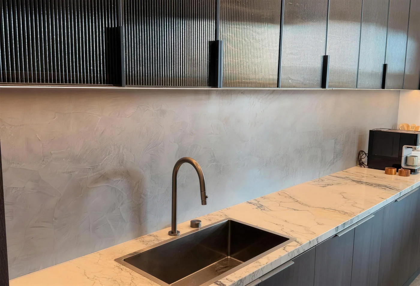 Polished plaster kitchen splashback with a brass tap and marble bench