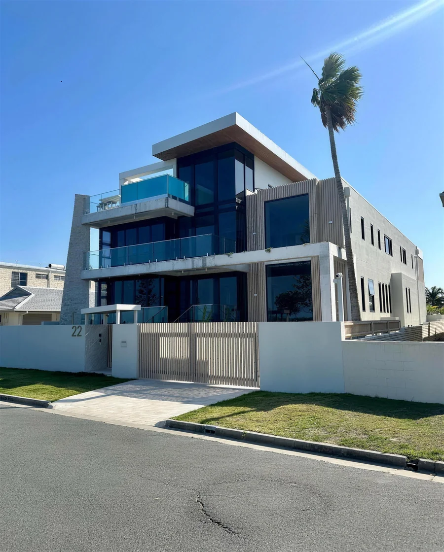 Three-storey rendered home with glass balustrades and a palm out front